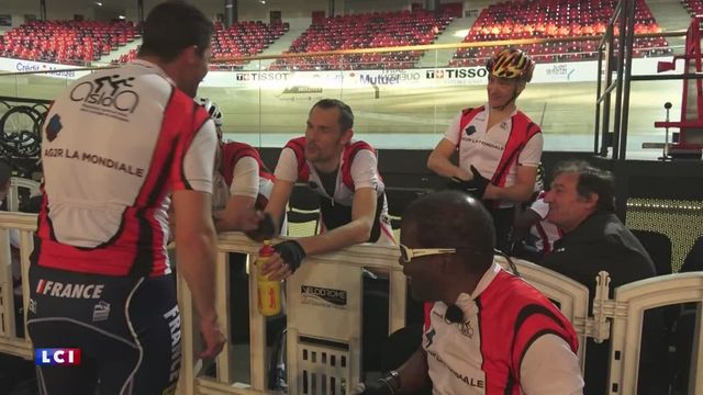 Photo de l'équipe réunie des cyclistes du club (Candide, Romain...) et les journalistes pilotes de LCI réunis autour d'une table à côté du vélodrome, tous en maillot aux couleurs de l'Aslaa